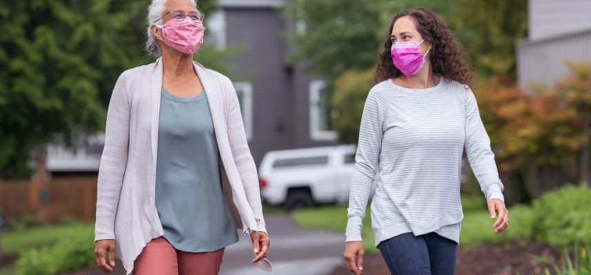Two women wearing protective face masks enjoying the outdoors during Coronavirus
